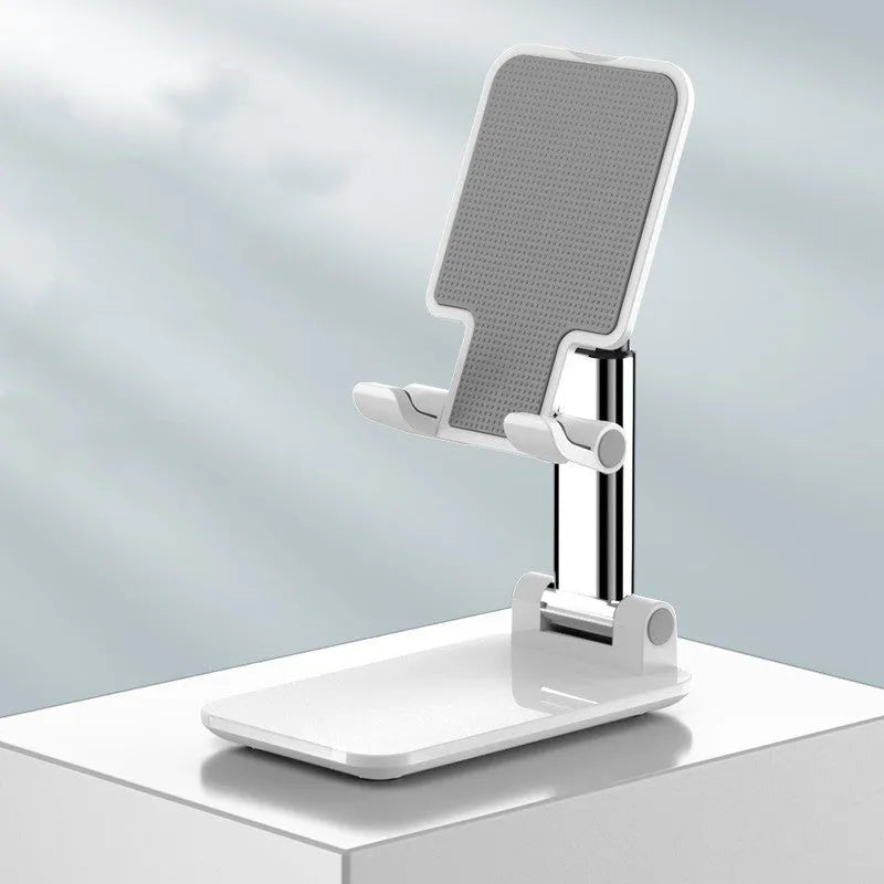 White folding telescopic mobile phone bracket holding a smartphone on a desktop.