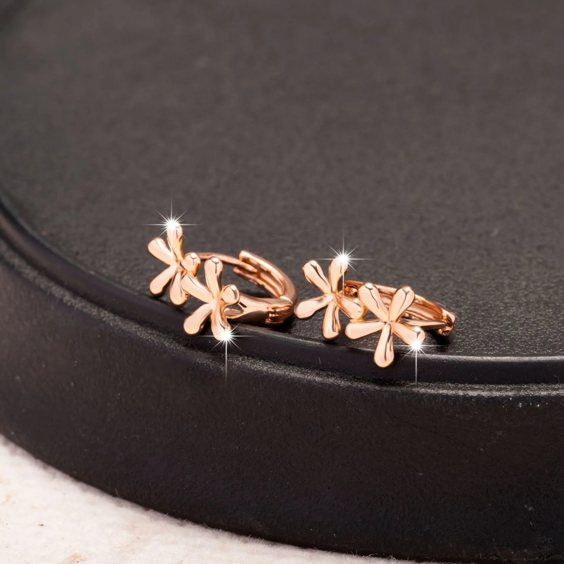 A pair of rose gold circular earrings featuring a waterdrop floral design with a fresh, sweet style.