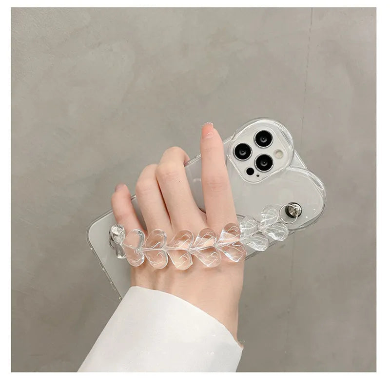 Clear iPhone case with transparent love heart bracelet charm attached, showing soft TPU material.