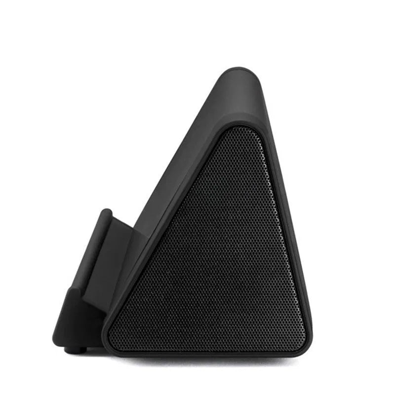 Small 5.5 cm round wireless Bluetooth speaker in black or white on a desk next to a mobile phone.