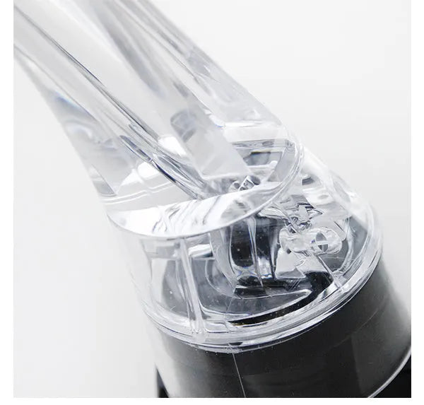 A clear acrylic wine aerator with a stainless steel filter, shown next to a wine glass.
