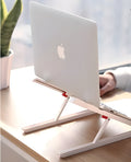 White foldable laptop stand on a desk, showing its elevated, angled position for ergonomic use.