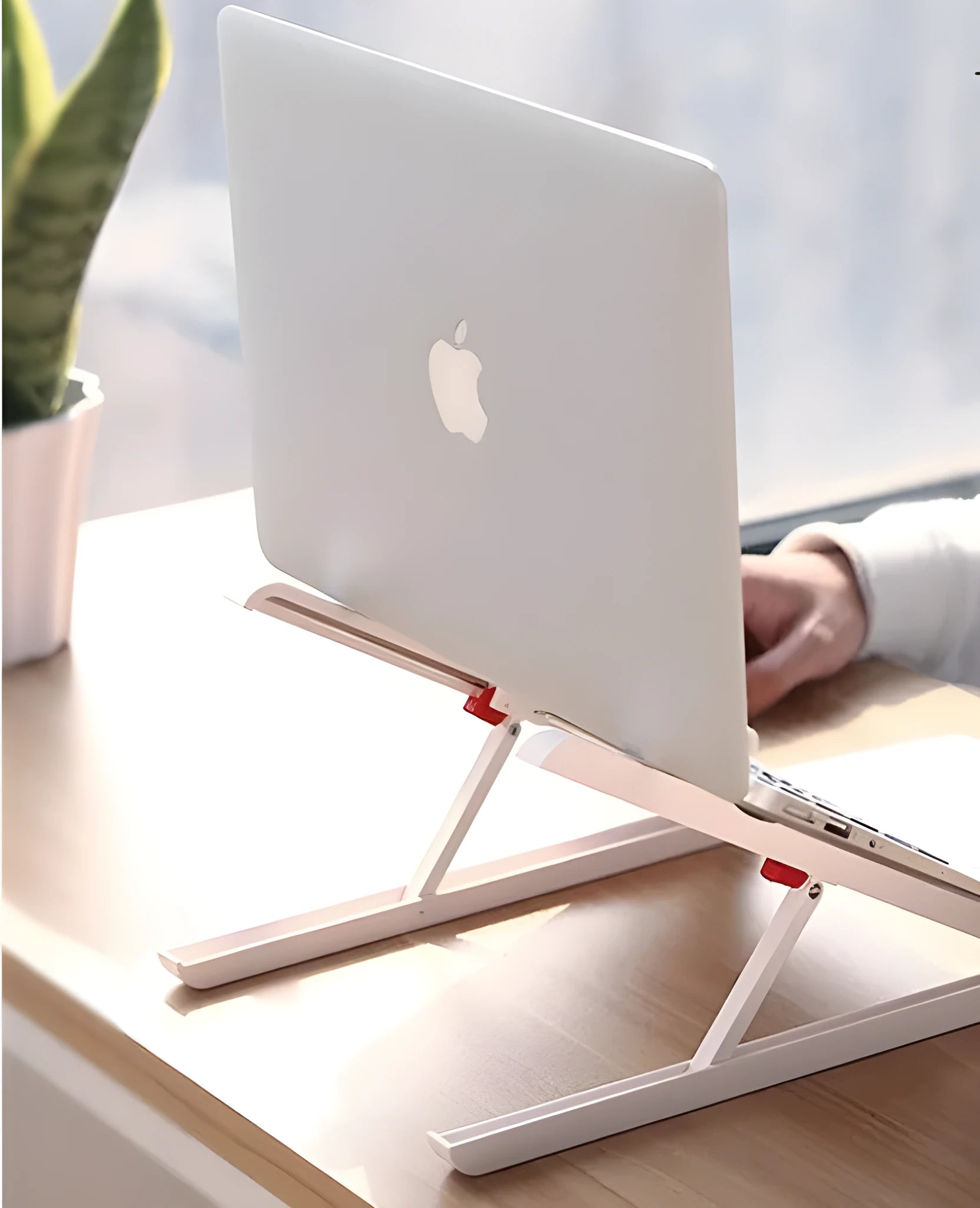 White foldable laptop stand on a desk, showing its elevated, angled position for ergonomic use.