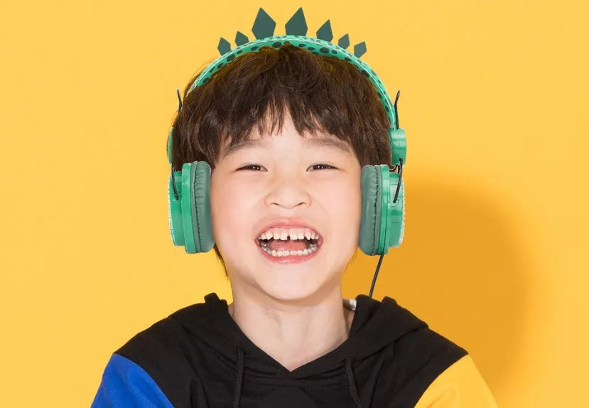 Green dinosaur children's headset with soft earmuffs and 3.5mm plug on a plain background