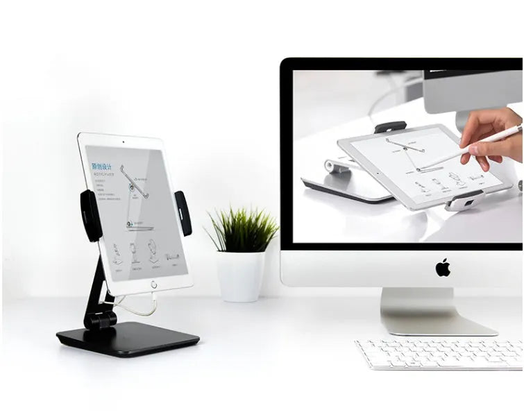 Silver foldable aluminium phone and tablet stand on a desk, holding a tablet at an angle.