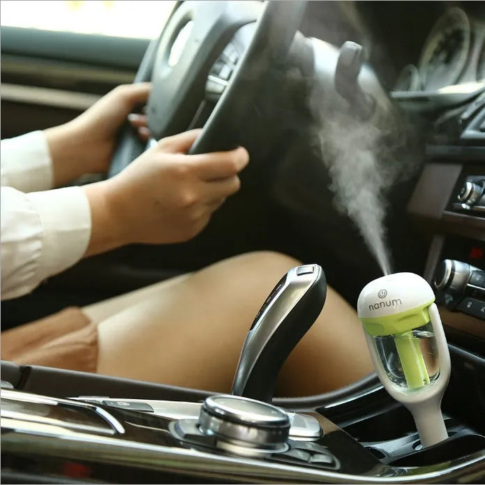 Compact blue portable car humidifier and essential oil diffuser with rotating nozzle on a car dashboard.
