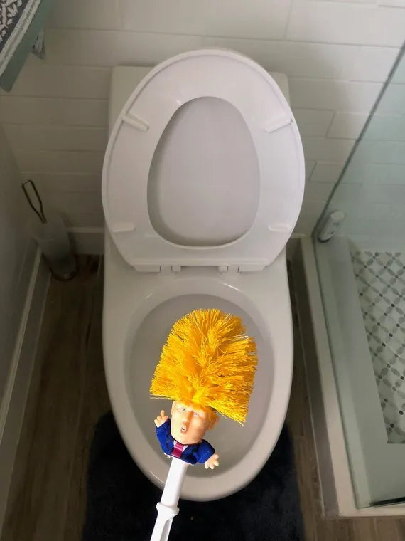 Yellow plastic Donald Trump toilet brush with hanging slot on handle.