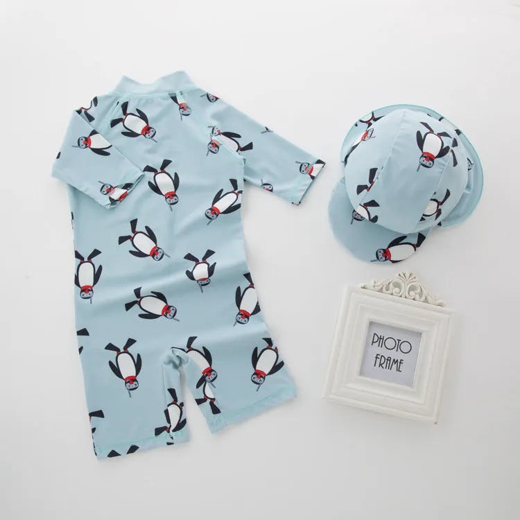Boys' blue and white penguin print long sleeve swimsuit with matching swimming cap laid flat.