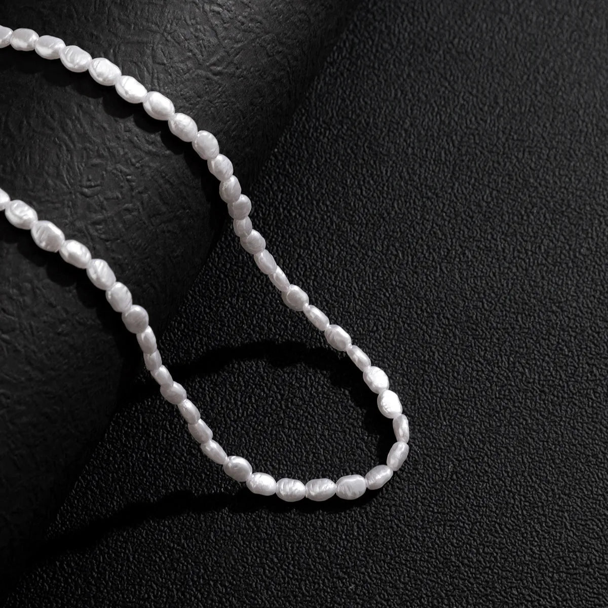 White U-shaped men's imitation pearl necklace with shellfish pendant on pearl chain.