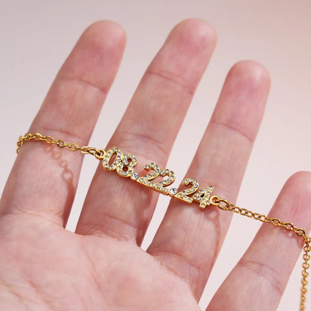 Stainless steel digital bracelet with diamond-studded numbers in gold finish on wrist.