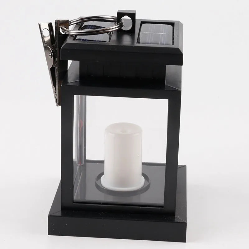 Solar LED candle light with black plastic shade, monocrystalline panel, and warm white illumination on garden path