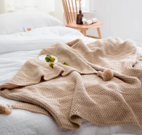 Acrylic knitted fringed blanket in beige colour on a sofa, showing texture and size.