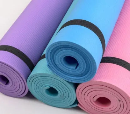 Red EVA fitness yoga mat with rolled edge showing thickness, laid flat on a wooden floor.
