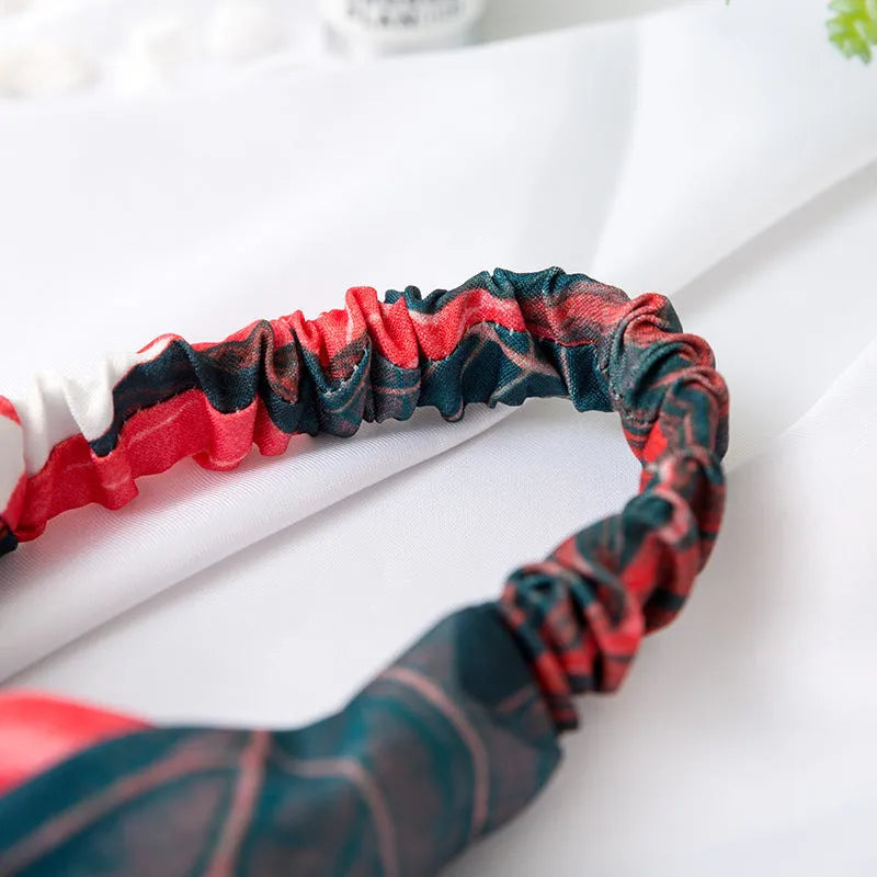 Red cloth women's headband with a banana leaf cross shaped hair decoration.