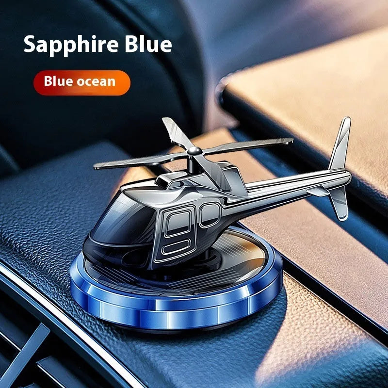 Silver solar-powered rotating metal car air freshener ornament on a dashboard.