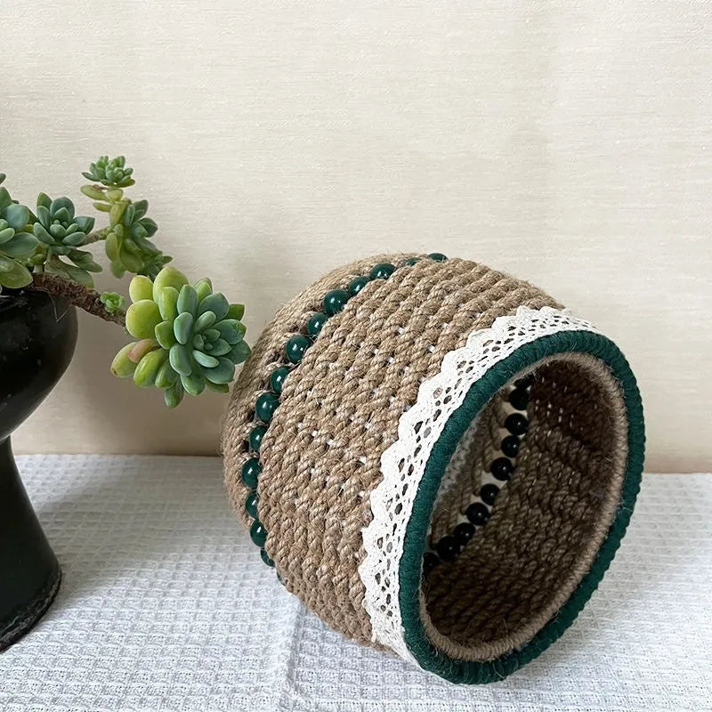 Hand woven rattan cylinder storage basket in solid green on a table, holding snacks and sundries