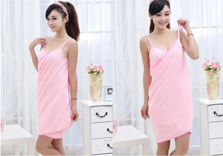 A person wearing a long pink polyester beach towel as a dress wrap at the seaside.