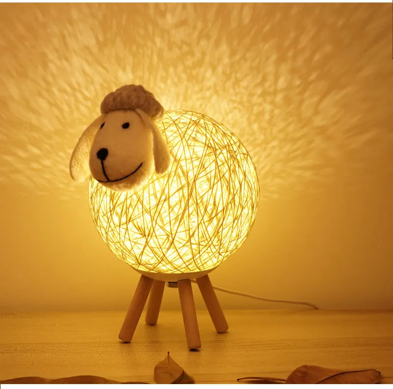 Hand-woven beige lamb night light with starry sky projection on a bedside table