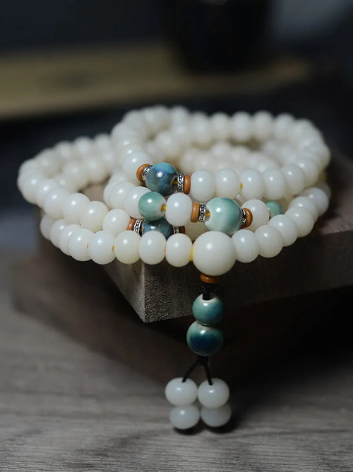 White jade bodhi root bracelet with 108 flat round beads in two sizes on wrist
