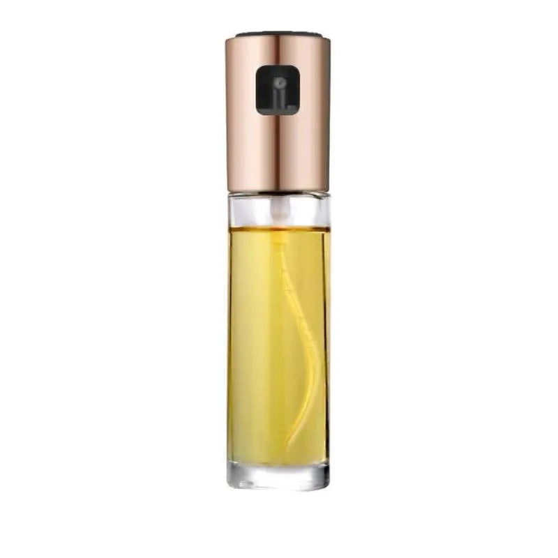 Gold pump-action oil and vinegar spray bottle with 100ml glass body on kitchen counter.