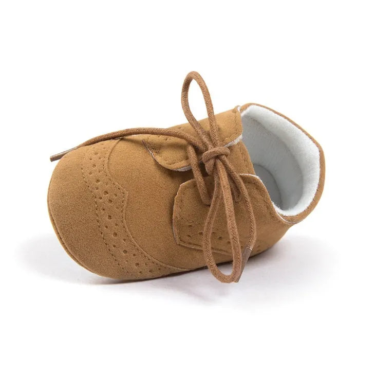 Vintage-style soft-soled baby shoes in black, grey, light brown, and white for infants 0-12 months.