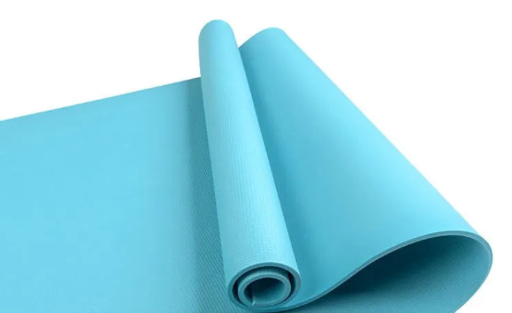 Red EVA fitness yoga mat with rolled edge showing thickness, laid flat on a wooden floor.