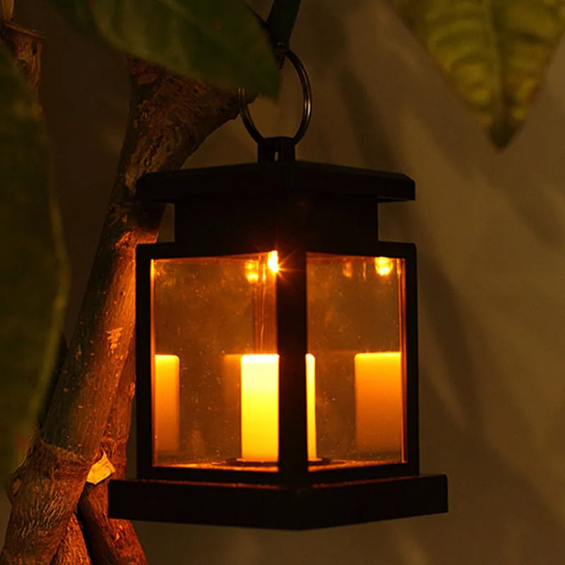 Solar LED candle light with black plastic shade, monocrystalline panel, and warm white illumination on garden path