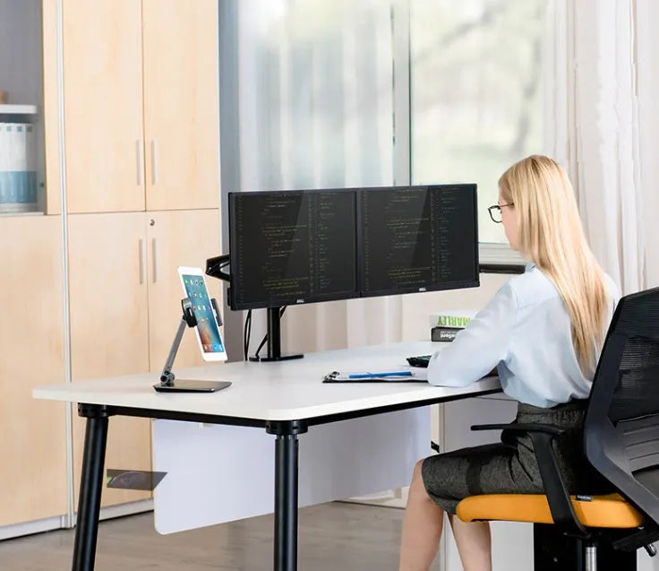 Silver foldable aluminium phone and tablet stand on a desk, holding a tablet at an angle.