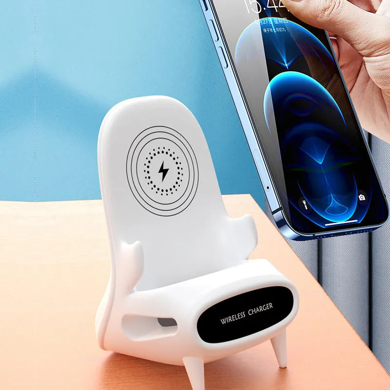 White chair-shaped wireless charging phone stand charging a smartphone on a desk