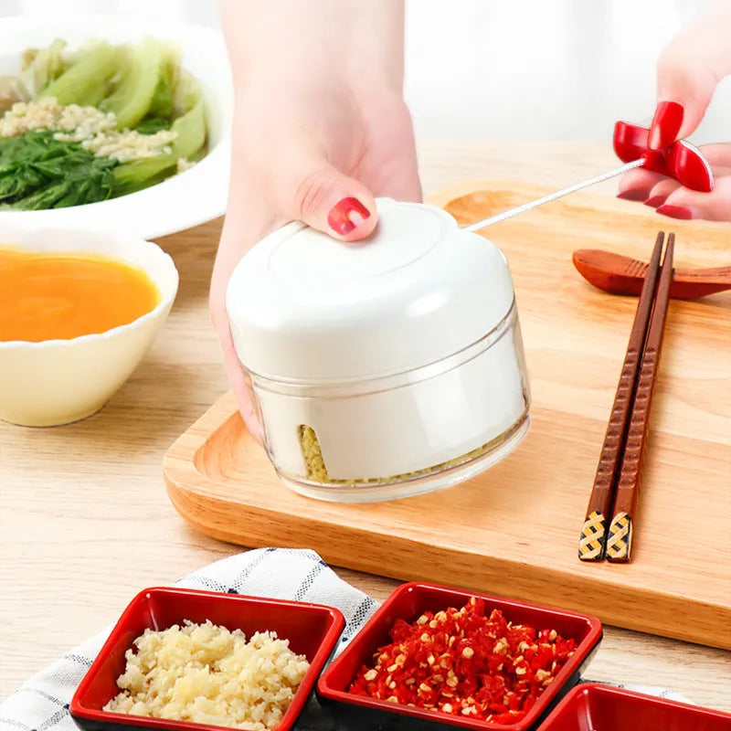 White and silver manual food chopper with stainless steel blades on a kitchen countertop.