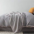 Small light grey polyester throw blanket folded, showing its rectangular 127cm by 170cm size.