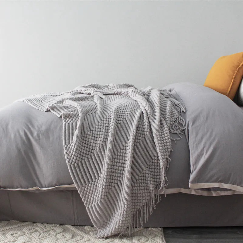 Small rectangular nap blanket in a neutral colour, showing its compact size relative to a hand.