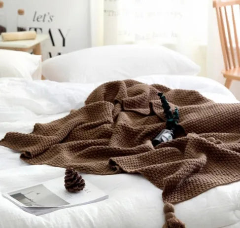 Acrylic knitted fringed blanket in beige colour on a sofa, showing texture and size.