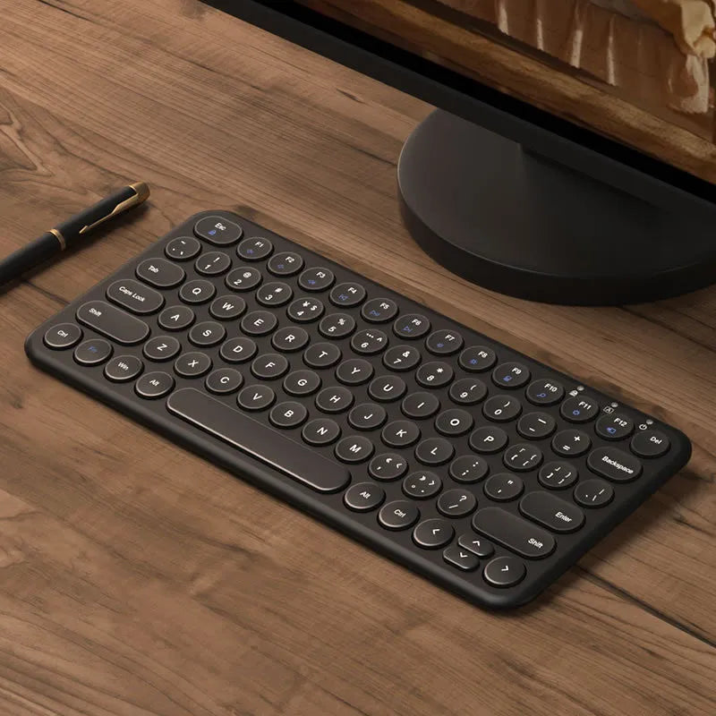 Ultra-thin white wireless keyboard and mouse set with USB dongle on a wooden desk.