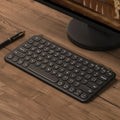 Ultra-thin white wireless keyboard and mouse set with USB dongle on a wooden desk.