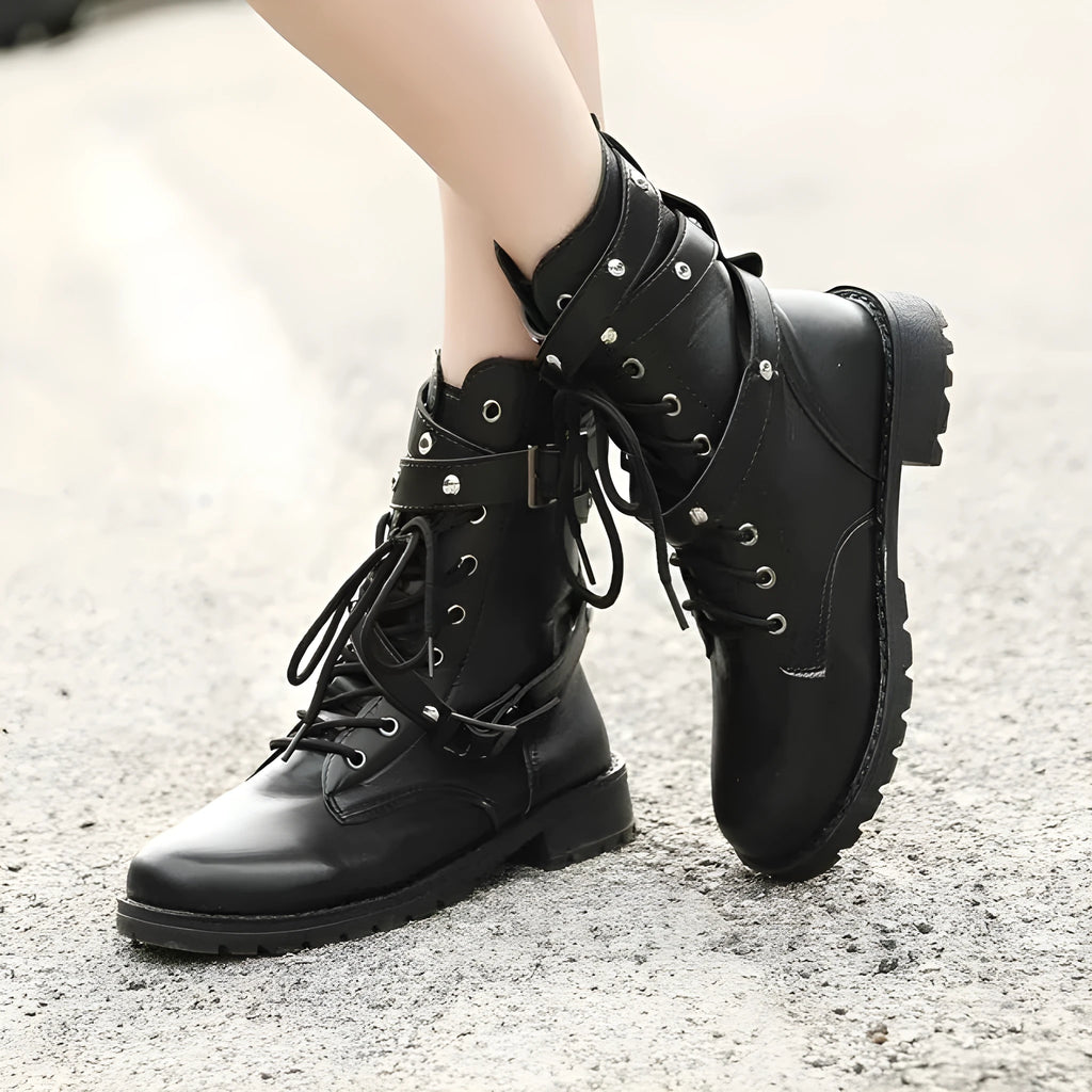 Women's black Martin motorcycle boots with low heel, lace-up front, round toe, and rivet and belt buckle detailing