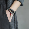 Ethnic black hair bracelet with white crystals and tassels showing bending lacing construction