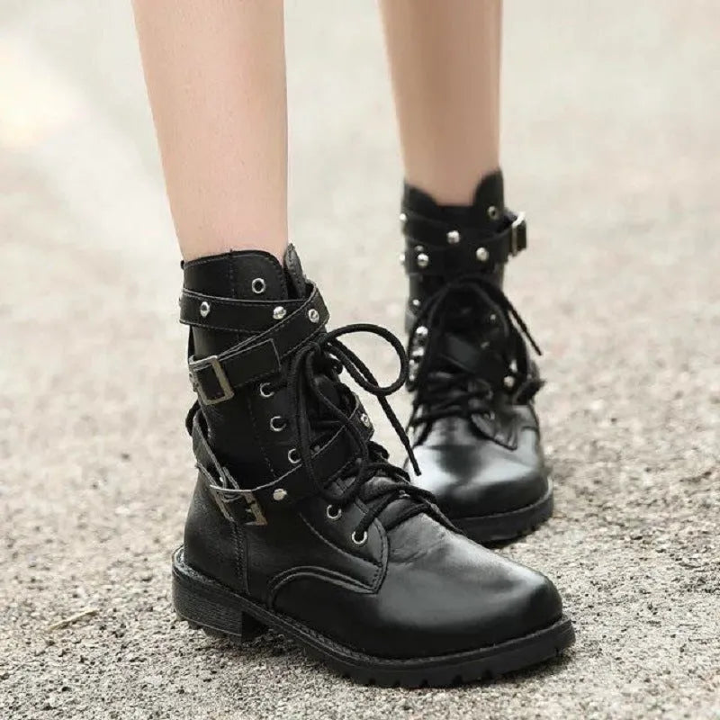 Women's black Martin motorcycle boots with low heel, lace-up front, round toe, and rivet and belt buckle detailing