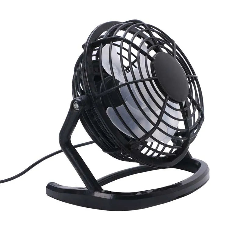 Small black USB desk fan with adjustable tilt on a wooden desk next to a laptop