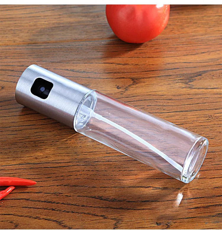 Gold pump-action oil and vinegar spray bottle with 100ml glass body on kitchen counter.
