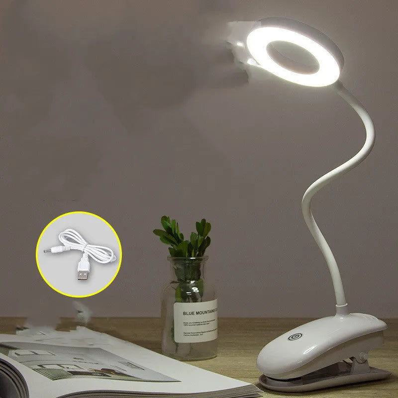 Modern clip-on rechargeable desk lamp with a white plastic shade and touch controls on its base.