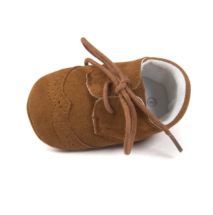 Vintage-style soft-soled baby shoes in black, grey, light brown, and white for infants 0-12 months.