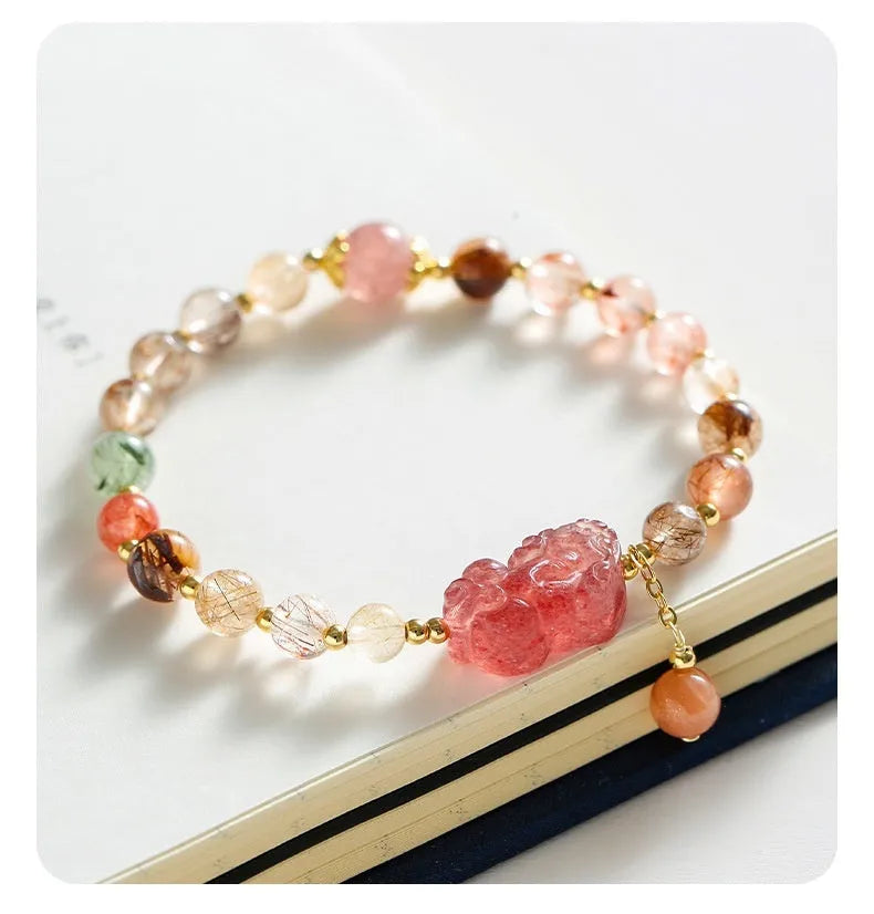 Copper women's bracelet with strawberry quartz crystal, Pixiu charm, and pearl accents on a white background.