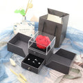 Blue jewellery gift box open showing a plastic eternal rose, with spaces for earrings and a necklace.