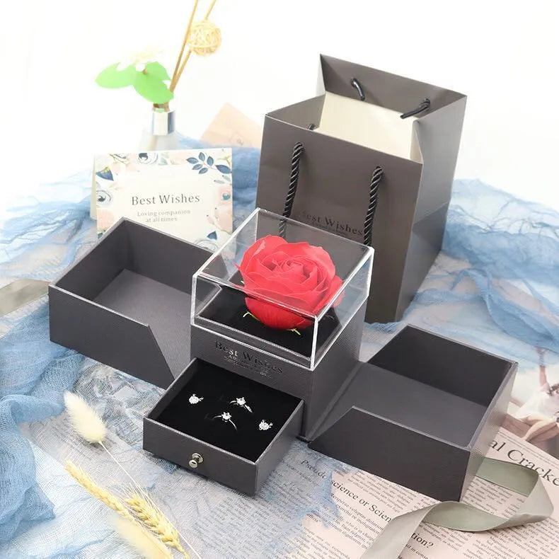 Blue jewellery gift box open showing a plastic eternal rose, with spaces for earrings and a necklace.