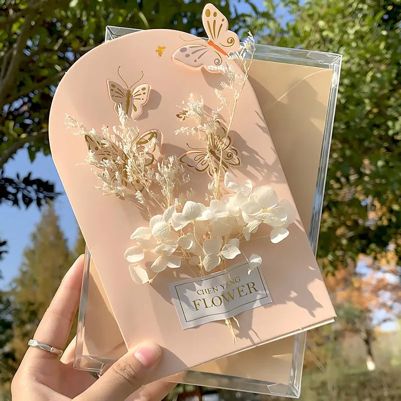 Handmade 3D butterfly-shaped greeting card with artificial flowers in a box, alongside its matching envelope.