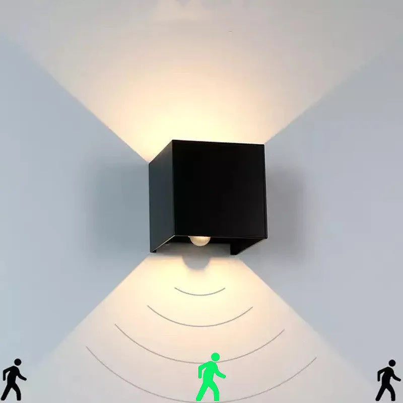 Square aluminium wall lamp in black on a corridor wall, showing adjustable colour temperature settings from warm to cool light.