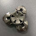 Close-up of a metallic alloy rotating fingertip gyro decompression toy on a table.