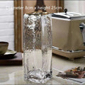 Transparent gold-painted glass vase on table with flower stems, 8x30cm size