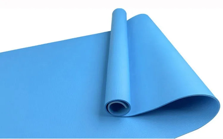 Red EVA fitness yoga mat with rolled edge showing thickness, laid flat on a wooden floor.